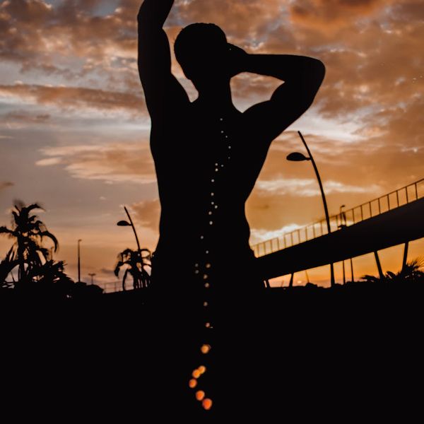 Person stretching outdoors during a sunrise with a vibrant sky.